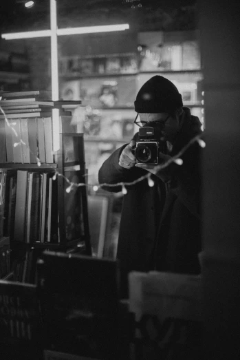 a black and white photo of a man holding a camera, by Cam Sykes, girl in a record store, medium format. soft light, with a mirror, a mysterious