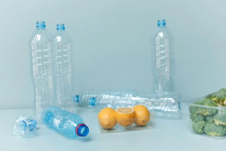 a bunch of plastic bottles sitting on top of a table, a still life, by Maeda Masao, pexels contest winner, plasticien, some orange and blue, with fruit trees, plain background, lemon