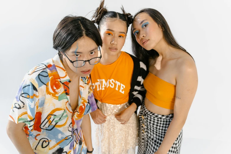 a group of three women standing next to each other, inspired by Wang Duo, trending on pexels, aestheticism, she looks like a mix of grimes, tilt and orange, half asian, makeup