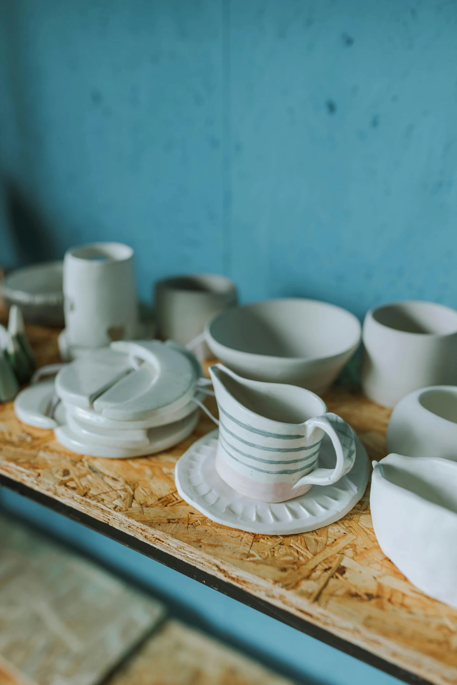 a table topped with bowls and plates on top of a wooden shelf, unsplash, process art, made of clay, introduction factory photo, thumbnail, made of glazed