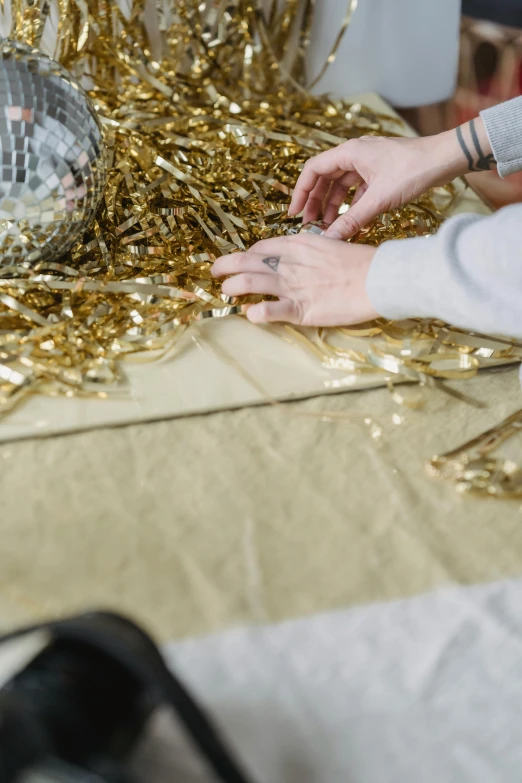 a woman sitting at a table with a disco ball in the background, process art, gold decorations, aerial view. hand stitching, ruffles tassels and ribbons, gif