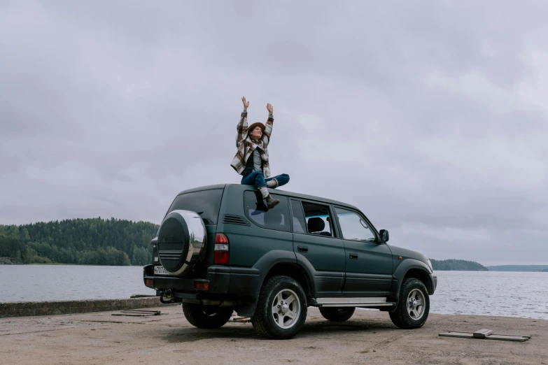 a couple of people standing on top of a truck, pexels contest winner, hands up, avatar image, car jump, woman