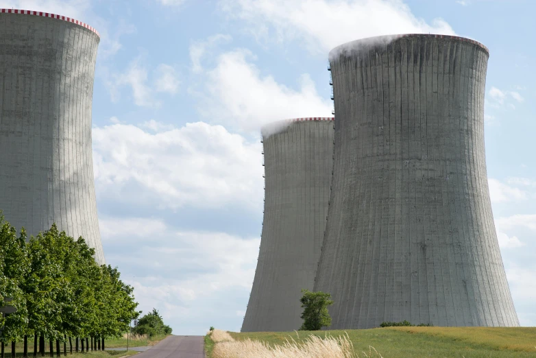 a couple of cooling towers sitting in the middle of a field, by Alison Geissler, pexels contest winner, nuclear art, close - up photo, shodan, giant columns, where a large