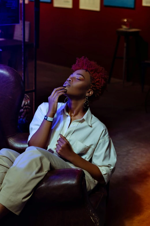 a woman sitting in a chair talking on a cell phone, inspired by Nan Goldin, trending on pexels, afrofuturism, praying with tobacco, attractive androgynous humanoid, woman with red hair, sitting in a lounge