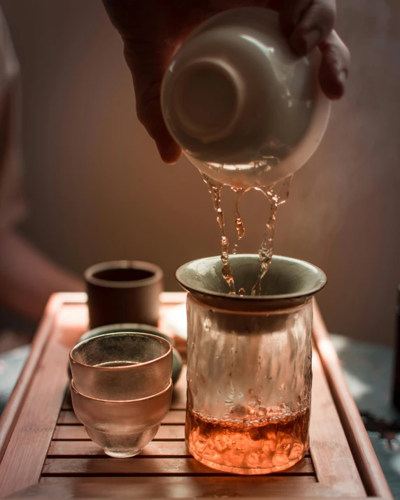 a person pours tea into a mason jar, by Adam Marczyński, trending on unsplash, process art, japanese onsen, square, carrying a tray, teapot : 1