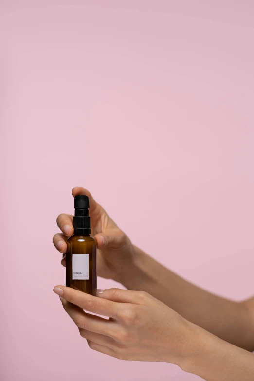 a woman holding a bottle of essential oil, a picture, by Will Ellis, unsplash, minimal pink palette, with textured hair and skin, thumbnail, back - shot