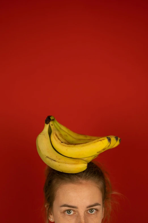 a woman with a bunch of bananas on her head, an album cover, trending on unsplash, red hat, patricia piccinini, high quality photo, made of food