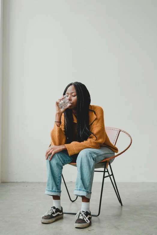 a woman sitting in a chair drinking from a cup, by Will Ellis, trending on unsplash, renaissance, sparkling water, plain background, she is wearing streetwear, standing water