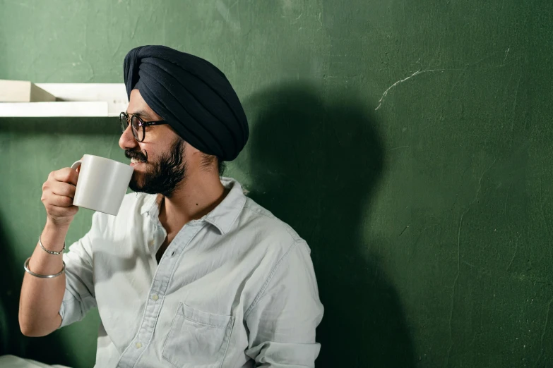 a man in a turban drinking a cup of coffee, inspired by Manjit Bawa, pexels contest winner, sitting in the classroom, blackboard, aussie baristas, background image