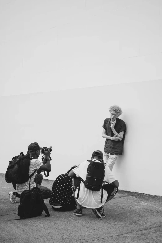 a black and white photo of a woman leaning against a wall, a black and white photo, by Joze Ciuha, small crowd of people, curly white hair, holding a camera, lil peep