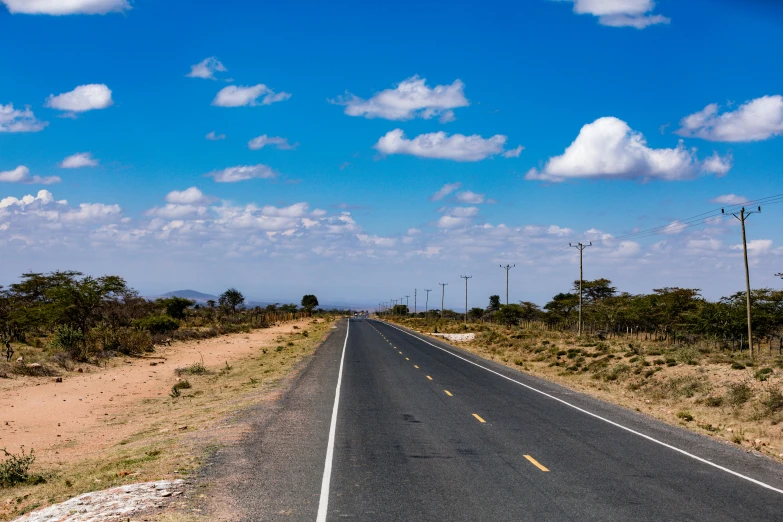 an empty road in the middle of the desert, by Peter Churcher, unsplash, hurufiyya, unmistakably kenyan, blue skies, thumbnail, in chuquicamata