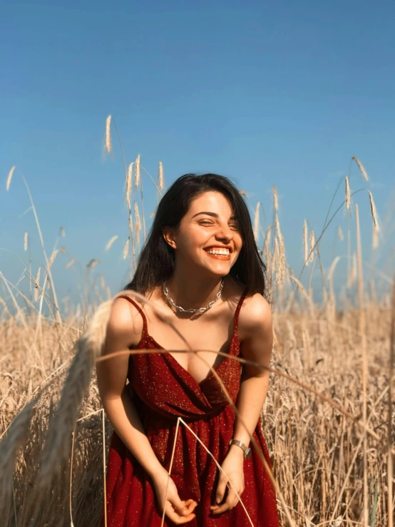 a woman standing in a field of tall grass, a picture, trending on pexels, smiling spartan, fair olive skin, wearing a red outfit, avatar image