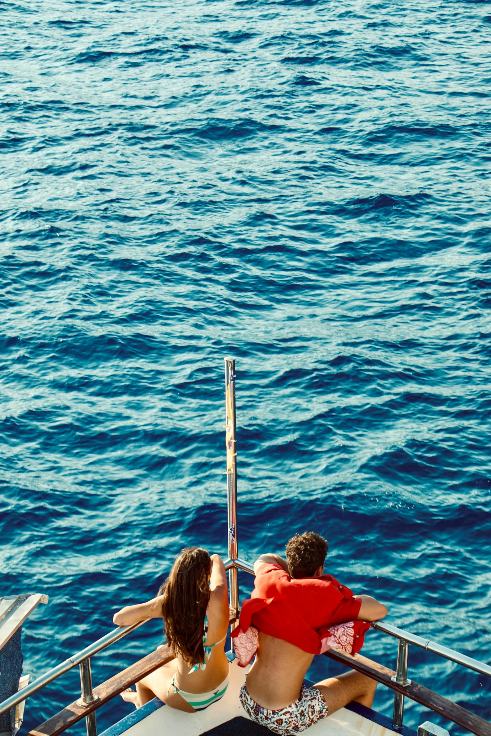 a couple of people that are sitting on a boat, middle of the ocean, looking down from above, banner, zoomed in