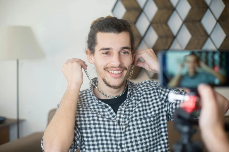 a man taking a picture of himself with a camera, by Adam Marczyński, trending on pexels, photorealism, earbuds jewelry, twitch emote, wearing a chain, smiling at the camera