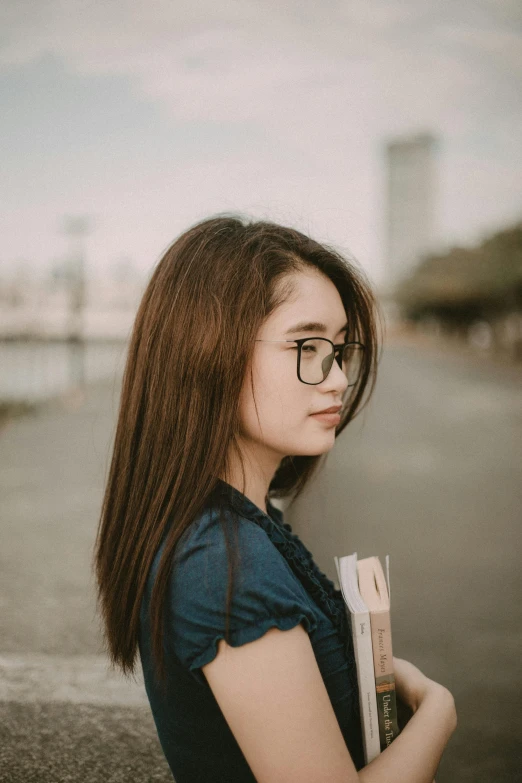 a woman with glasses is holding a book, by Tan Ting-pho, side portrait of a girl walking, square face, high-quality photo, medium hair