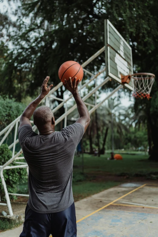 a man standing on top of a basketball court holding a basketball, pexels contest winner, shaq, playing games, at a park, at home