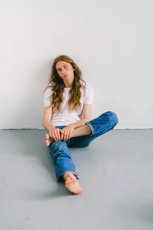 a woman sitting on the floor with her legs crossed, an album cover, by Sara Saftleven, renaissance, baggy jeans, with long hair, androgynous male, ryan mcginley