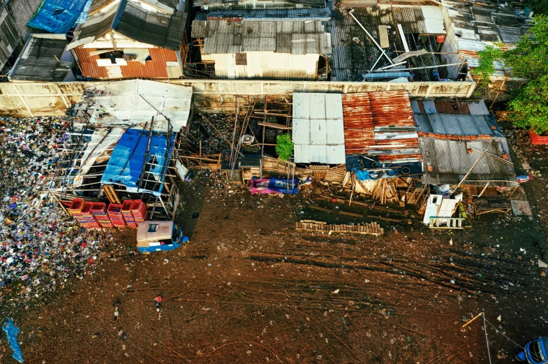 a large pile of trash sitting on top of a dirt field, unsplash, hurufiyya, houses on stilts, helicopter view, manila, thumbnail