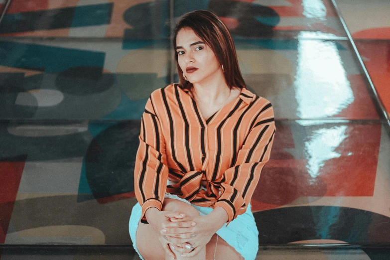 a woman sitting on a bench with her legs crossed, a colorized photo, pexels contest winner, orange neon stripes, ameera al-taweel, striped shirt, closeup portrait shot