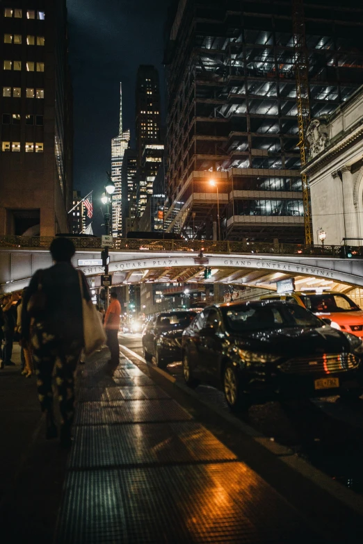 a person walking down a city street at night, under bridge, cars and people, modern chicago streets, 2019 trending photo