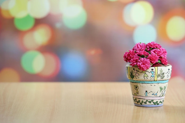 a flower pot sitting on top of a wooden table, by Lucia Peka, trending on pixabay, pink lighting, carnation, bokeh backdrop, brightly coloured