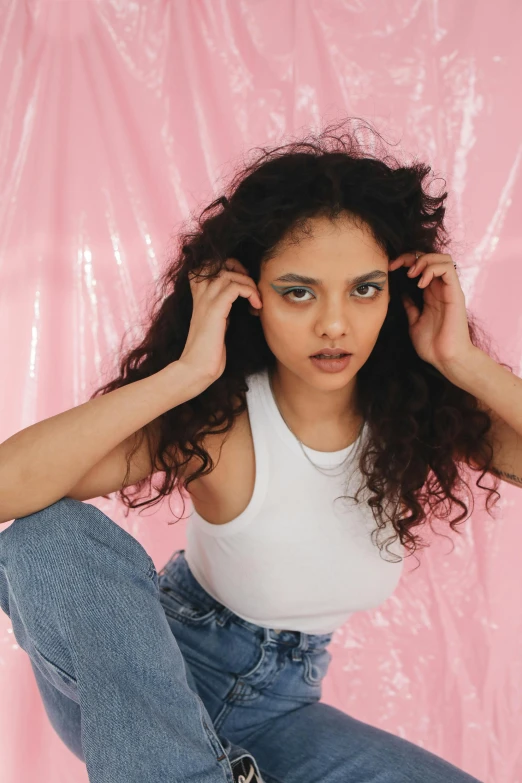 a beautiful young woman sitting on top of a skateboard, an album cover, trending on pexels, renaissance, long wild black curly hair, pink studio lighting, tessa thompson inspired, pastel clothing