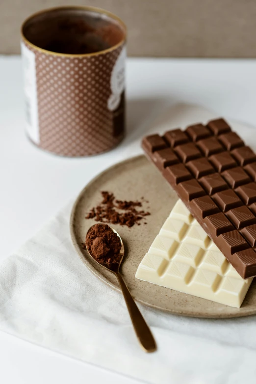 a chocolate bar sitting on top of a plate next to a cup of coffee, product image