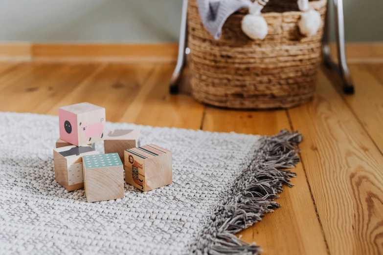 a toy sitting on top of a rug on top of a wooden floor, inspired by Josef Block, trending on pexels, wooden crates, light grey, miniature product photo, blocks