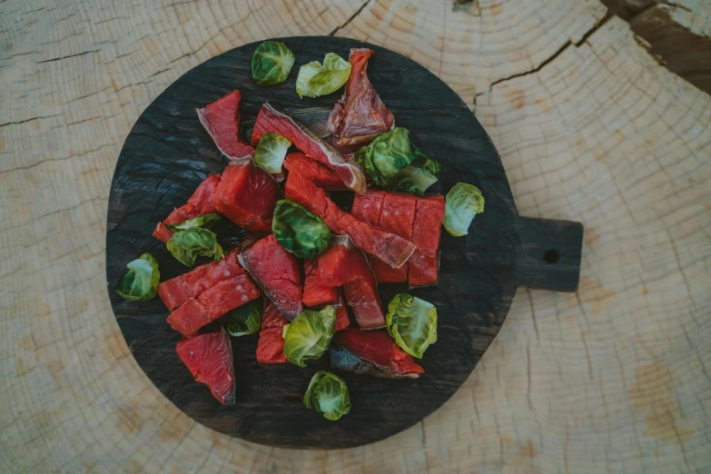 a black plate topped with watermelon and brussels sprouts, pexels contest winner, hurufiyya, red meat shreds, on wooden table, bells, hunting