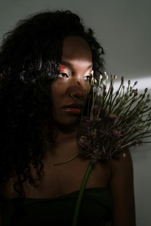 a woman holding a bunch of flowers in front of her face, an album cover, by David Palumbo, unsplash, visual art, brown skin. light makeup, dramatic lowkey studio lighting, ((portrait)), sza