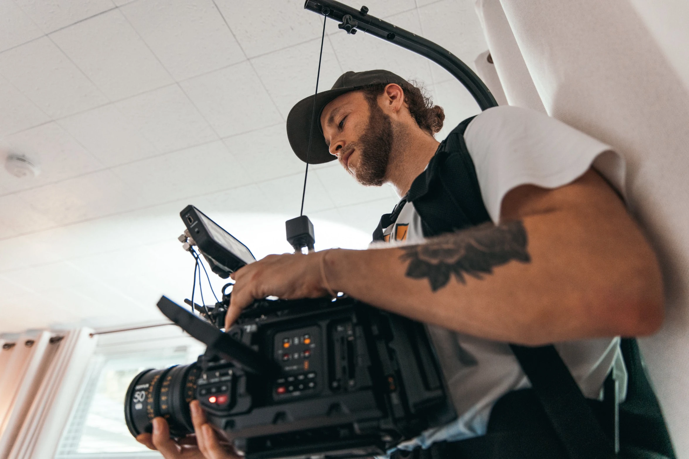 a man holding a camera in a room, production ig, shot from the side, digitigrade, looking down on the camera