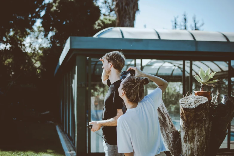 a couple of people that are standing in the grass, pexels contest winner, visual art, exterior botanical garden, looking at the ceiling, looking outside, sunny day time