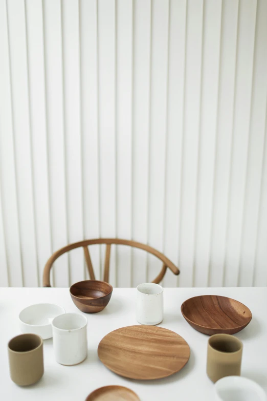 a white table topped with bowls and plates, inspired by Constantin Hansen, minimalism, walnut wood, environmental shot, dwell, 9