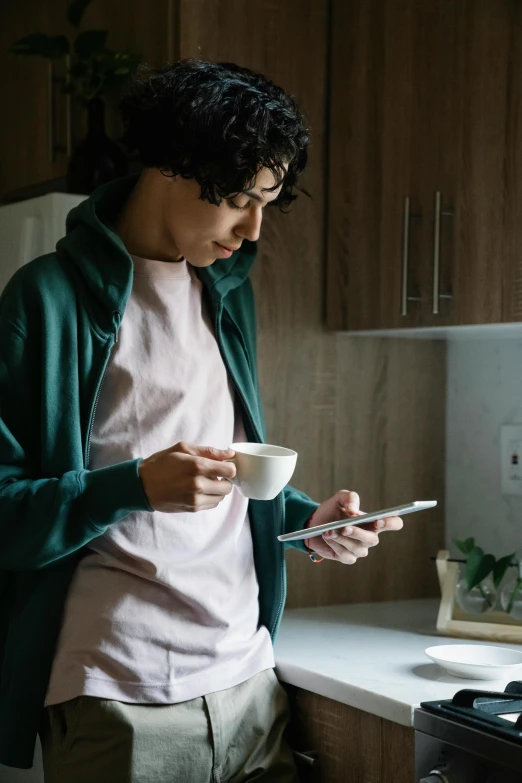 a man standing in a kitchen looking at his cell phone, a cartoon, trending on pexels, portrait of morning coffee, an asian woman, modern photo, long sleeves