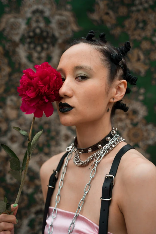 a close up of a person holding a flower, an album cover, inspired by Xia Chang, trending on pexels, international gothic, non binary model, wearing chains, mixed-race woman, black peonies