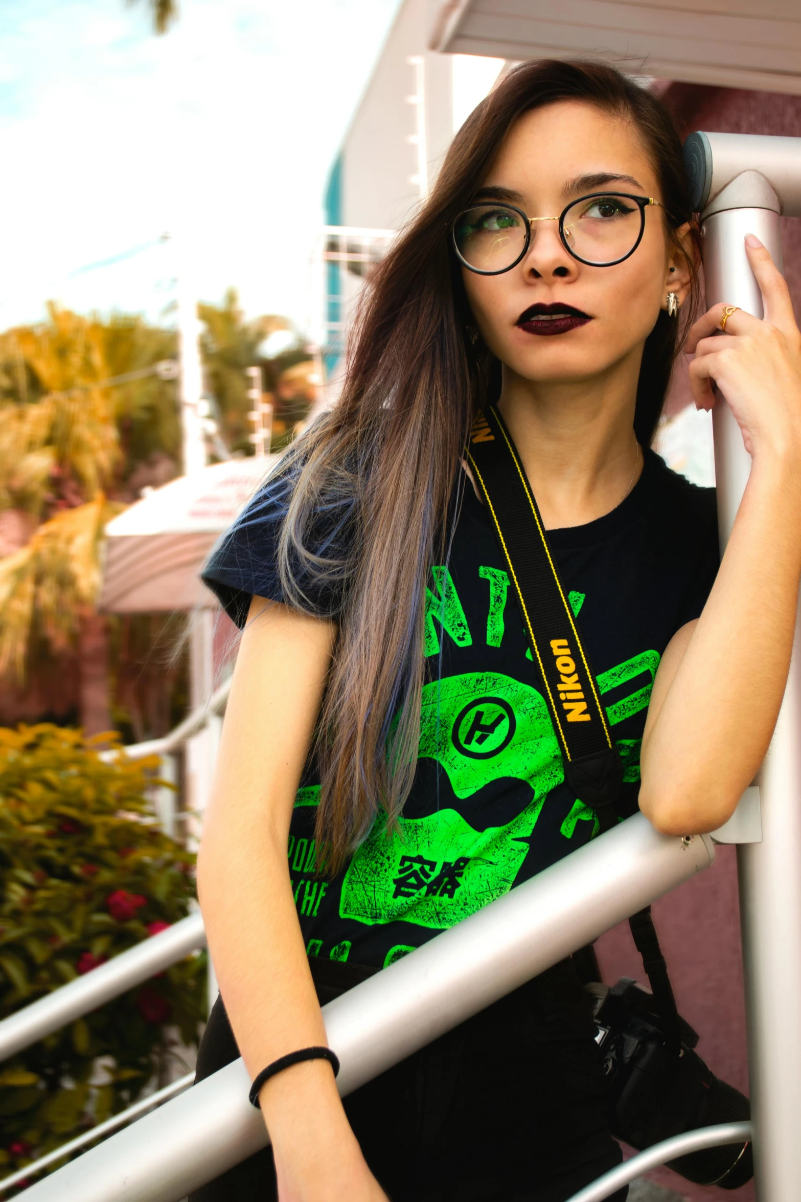a woman with glasses leaning on a railing, trending on pexels, graffiti, zendaya as she-hulk, gothic clothing, graphic tees, shot on nicon camera