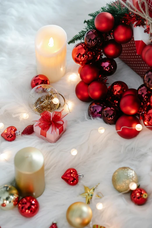 a christmas wreath sitting on top of a snow covered ground, in a room full of candles, hearts, toys, gold and red accents