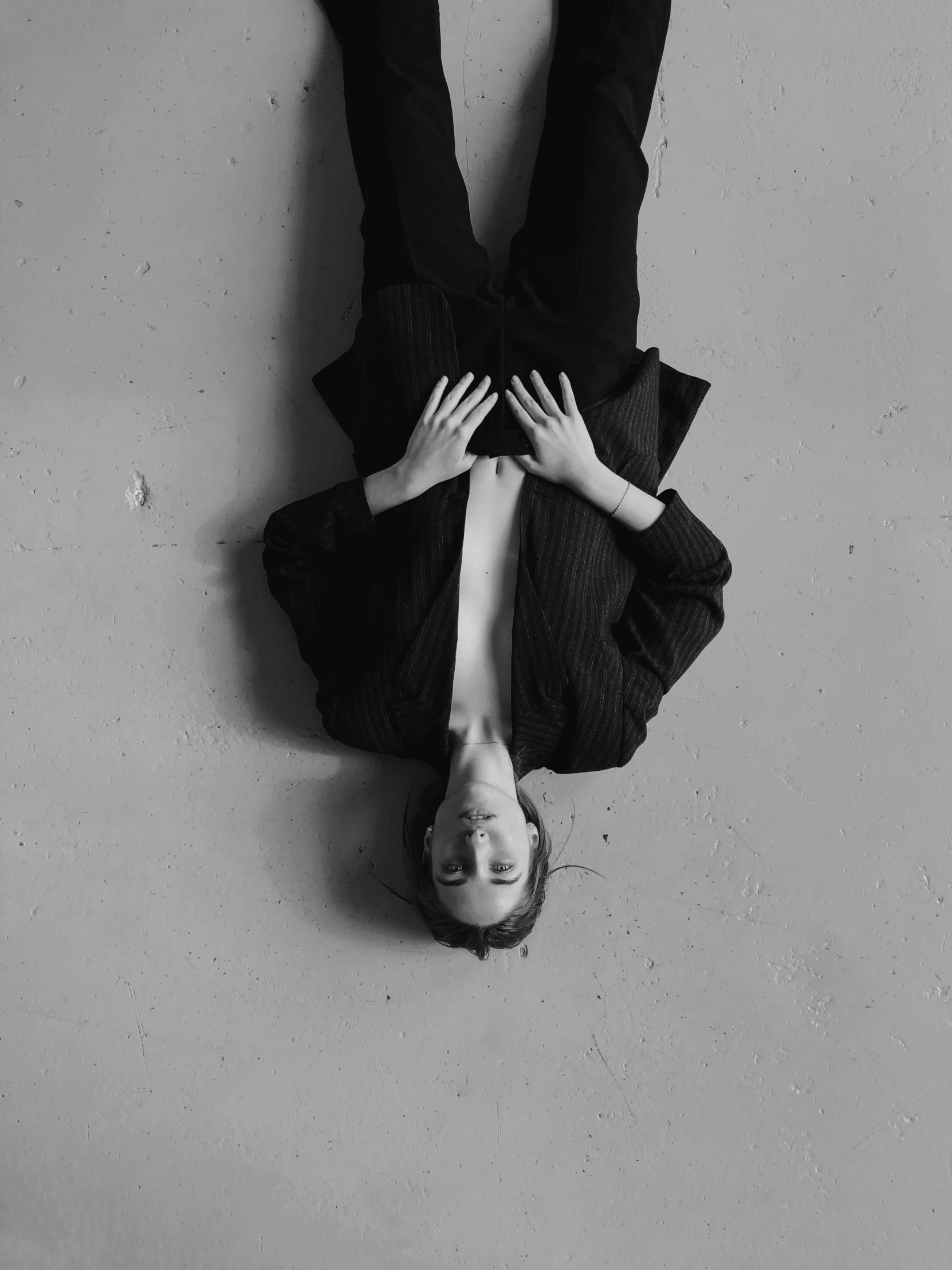 a black and white photo of a person upside down, a black and white photo, unsplash, wearing black suit, androgyny, resting, ilustration