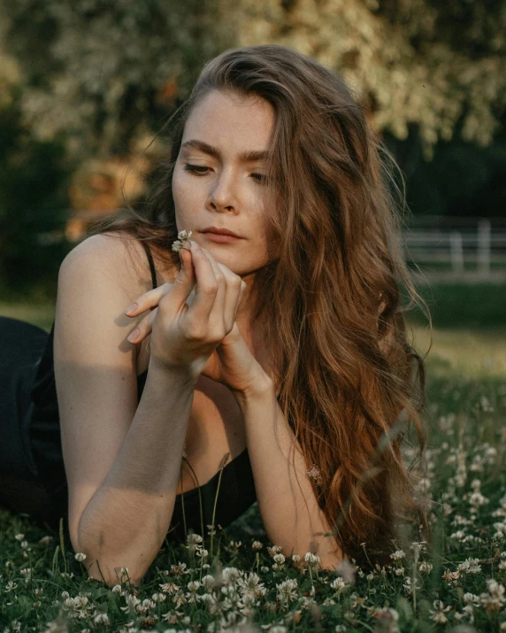 a woman laying on top of a lush green field, inspired by Elsa Bleda, trending on pexels, renaissance, brown flowing hair, pouting, low quality photo, queer woman