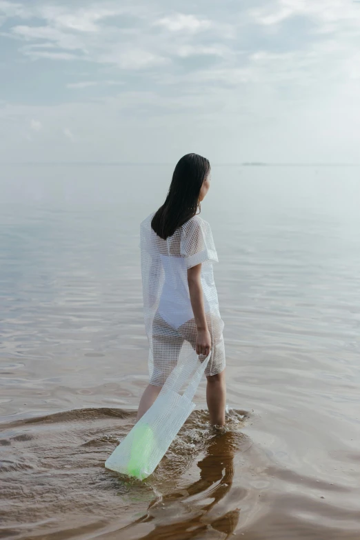 a woman standing in the water with a surfboard, inspired by Ren Hang, unsplash, conceptual art, ao dai, made out of plastic, white clothes, slide show