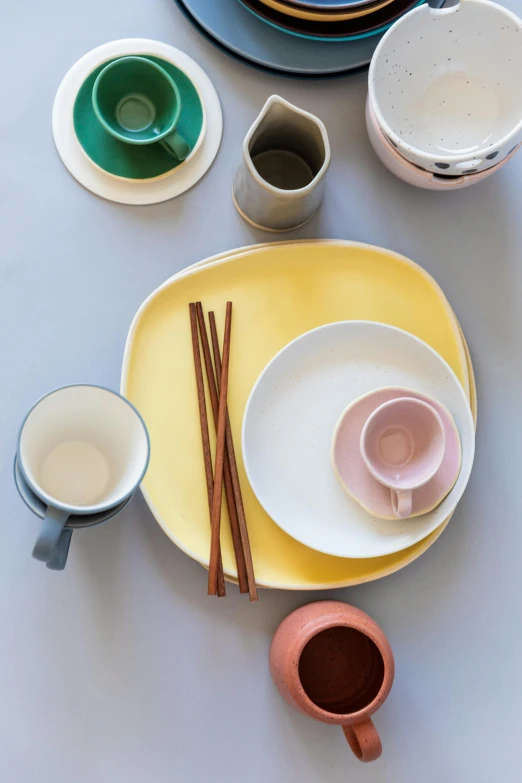 a table topped with plates and bowls and chopsticks, inspired by Giorgio Morandi, instagram, gradient yellow, square, coffee cup, multi pastel colors