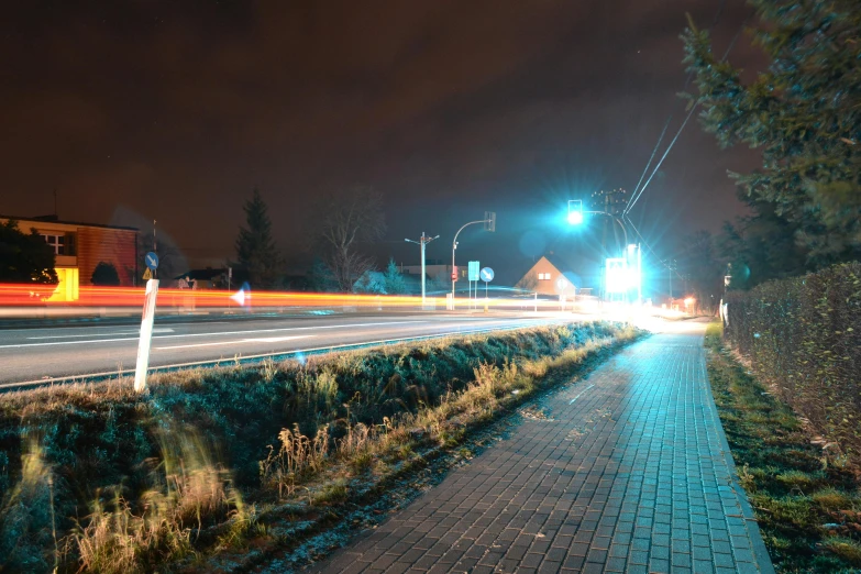 a red fire hydrant sitting on the side of a road, a picture, by Adam Marczyński, traffic with light trails, in a suburb, street of teal stone, thumbnail