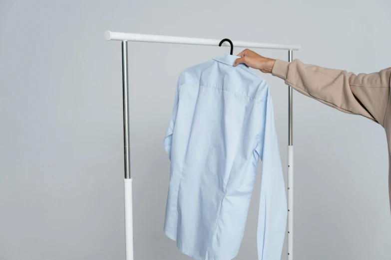 a woman standing next to a rack with a shirt on it, inspired by Bela Čikoš Sesija, quick assembly, view from bottom to top, medium - shot, maintenance