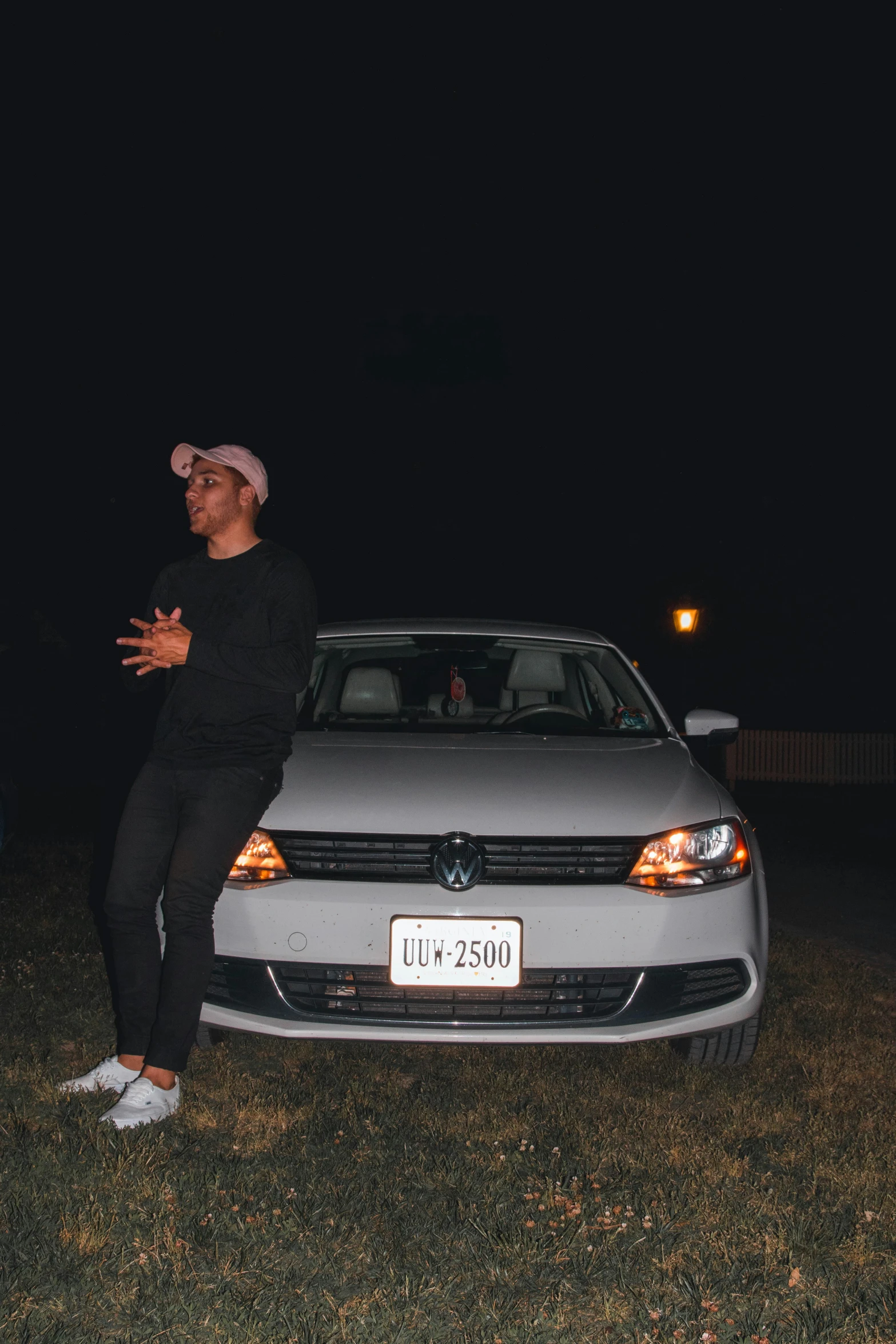 a man standing next to a white car at night, an album cover, by Austin English, unsplash, realism, rapper, ☁🌪🌙👩🏾, sassy pose, leaked photo