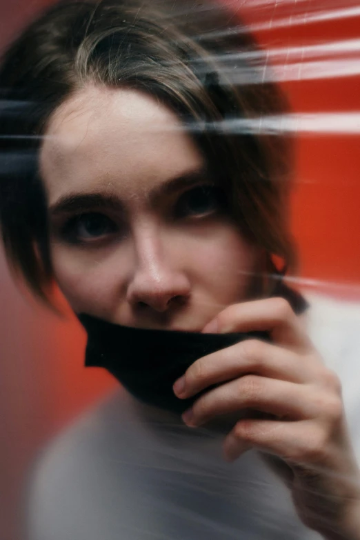 a woman holding a cell phone to her ear, by Adam Marczyński, trending on pexels, realism, wearing turtleneck, holding a red banner, todd hido, feral languid emma roberts