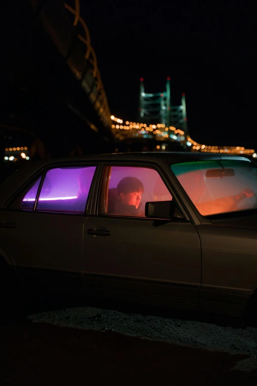 a car parked in front of a bridge at night, an album cover, pexels contest winner, violet and aqua neon lights, portait photo, frank moth, inside of a car