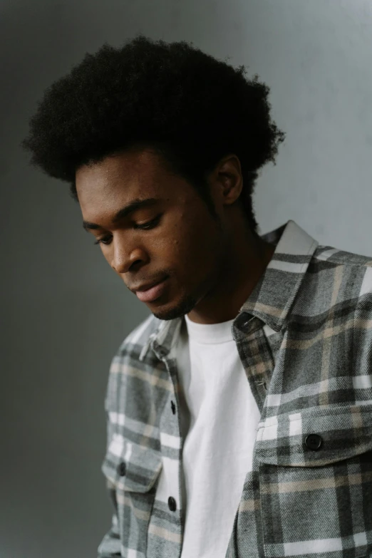 a man looking down at his cell phone, an album cover, by Cosmo Alexander, trending on pexels, renaissance, wearing plaid shirt, headshot profile picture, afro, grayish
