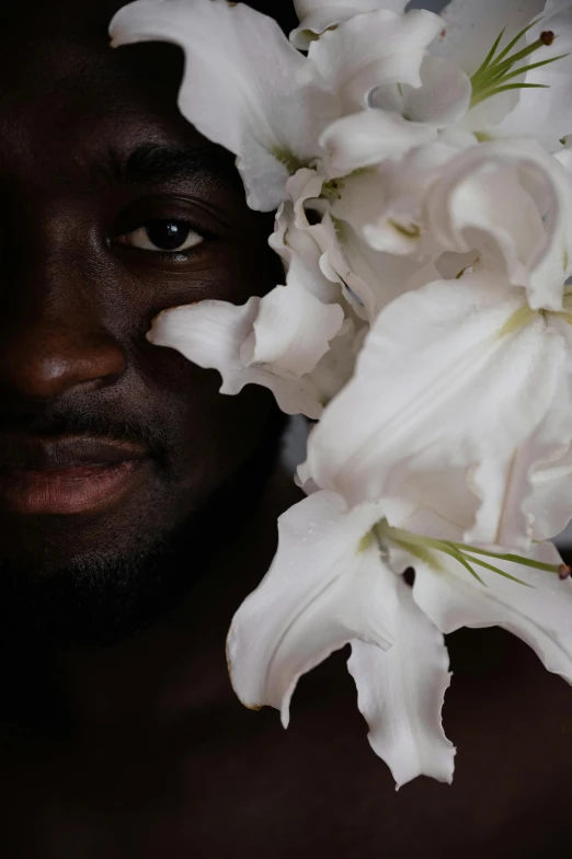 a man holding a bunch of white flowers, an album cover, inspired by Robert Mapplethorpe, pexels contest winner, african facial features, ( ( dark skin ) ), close up face detail, lilies