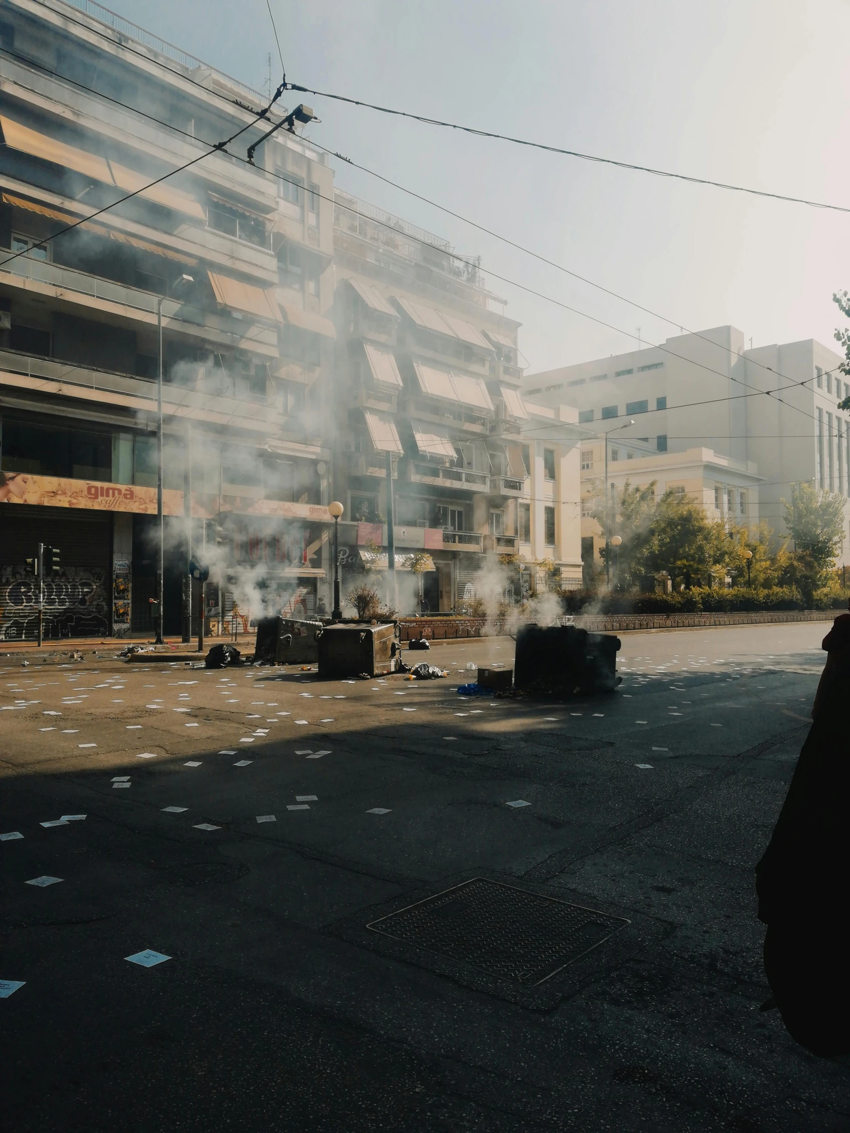 a man standing in the middle of a street with smoke coming out of his mouth, by Alexis Grimou, athens in the background, crates and parts on the ground, photograph taken in 2 0 2 0, firing it into a building