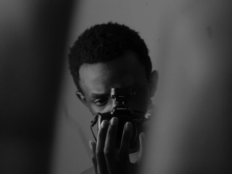 a man taking a picture of himself in a mirror, a black and white photo, by Afewerk Tekle, pexels contest winner, realism, headshot profile picture, spiky black hair and dark skin, spying, shot on red camera